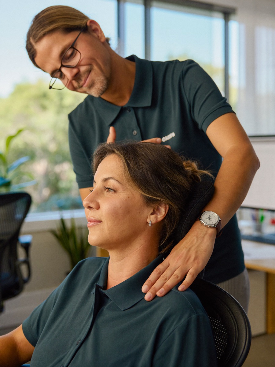 Fisioterapeuta de Fisia dando un masaje cervical a una trabajadora en su oficina